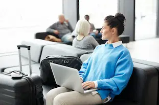 Business traveler working on laptop at airport lounge